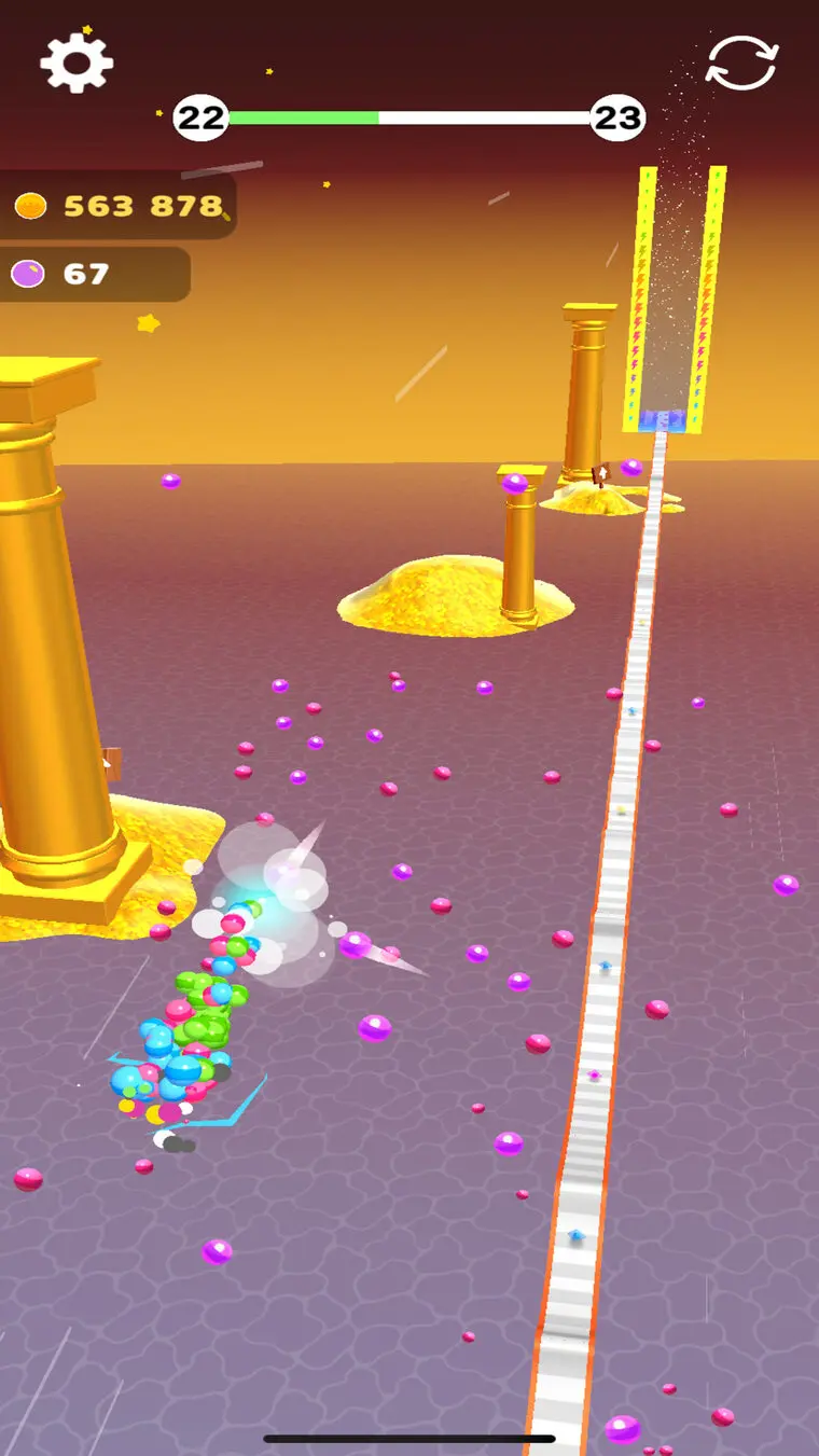 Schermata di Balls Go High: sfere rosa e viola sparse su un pavimento scuro davanti a colonne dorate, con un raggio luminoso verticale, tramonto arancione sullo sfondo.